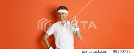 Concept of sport, fitness and lifestyle. Portrait of confident middle-aged sportsman, showing okay sign and look pleased, guarantee something or recommending gym, orange background 99593721