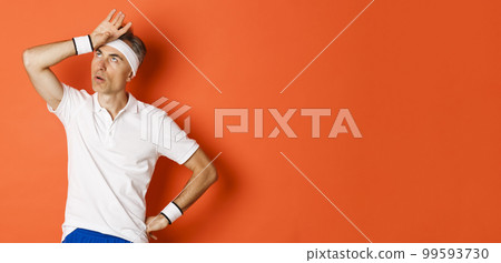 Concept of sport, fitness and lifestyle. Portrait of annoyed male athlete, roll eyes and facepalm, looking bothered, standing over orange background Concept of sport, fitness and lifestyle. Portrait of annoyed male athlete, roll eyes and facepalm, looking bothered, standing over orange background 99593730