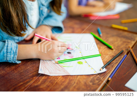 Close up hands of little girl draw and paint the picture on paper and sit near her friend in class Close up hands of little girl draw and paint the picture on paper and sit near her friend in class 99595125