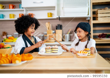 Two little girls, African American and Asian girls use wooden spoon and fork to play and fun Two little girls, African American and Asian girls use wooden spoon and fork to play and fun 99595150