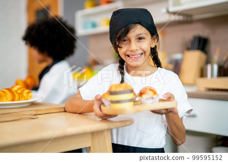 Little lovely girl hold plate contain cupcake and look at camera with smiling during study Little lovely girl hold plate contain cupcake and look at camera with smiling during study 99595152