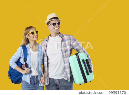 Young couple who are going on summer holiday looking at copy space on yellow background 99595870