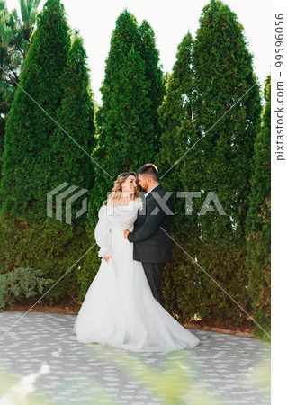 the bride and groom hugging and dancing in the park.  99596056