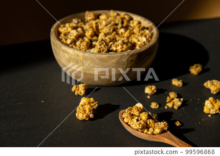 Homemade granola with nuts and seeds in eco tableware wooden bowl. Healthy snack on breakfast. Muesli from oatmeal, raisins, honey, cranberry, flax, almond, cashew, freshly baked 99596868