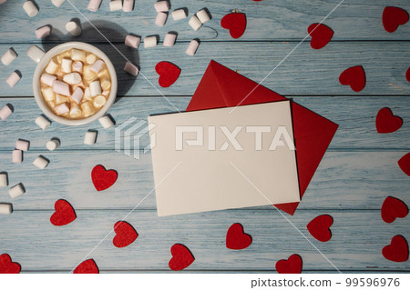 Greeting or invitation card mock up with red envelope with white cup of coffee and marshmallows on wooden background. Romantic Small hearts Valentine day. Blank paper card copy space for your text. 99596976
