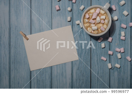 Empty greeting or invitation card mock up with white cup of coffee and marshmallows on wooden blue background. Blank paper copy space for your text. Valentines day, Happy fathers mothers day, Womens 99596977