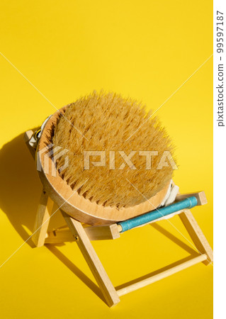 Dry massage brush on beach chair with natural bristle, ecological cosmetics, home care. Bamboo Brush for dry anti-cellulite massage. Spa beauty concept Dry massage brush on beach chair with natural bristle, ecological cosmetics, home care. Bamboo Brush for dry anti-cellulite massage. Spa beauty concept 99597187
