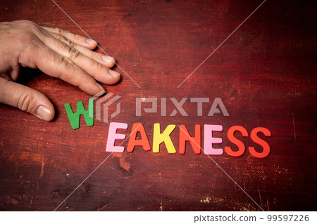 WEAKNESS. Text from colorful alphabet letters on wooden background 99597226