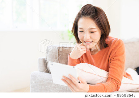 一個女人看著平板電腦微笑 99598643