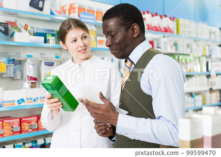 druggist explaining prescribed medicine to man 99599470