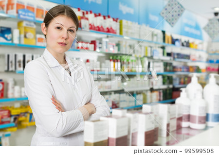 pharmacist standing with arms crossed in pharmacy 99599508
