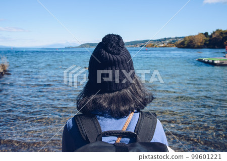 Back view of Asian girl traveling in Taupo with the scenery view of Lake Taupo the largest fresh water lake in New Zealand. 99601221