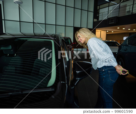 Caucasian woman looking out the car window in a car dealership. Caucasian woman looking out the car window in a car dealership. 99601590