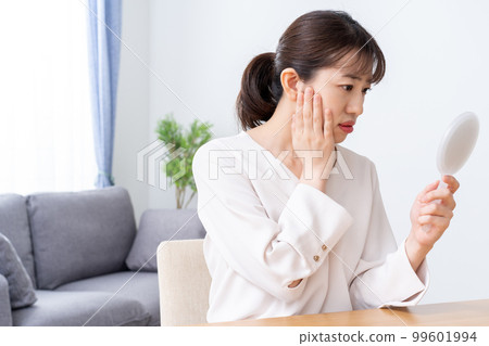 A woman who checks skin troubles with a hand mirror 99601994