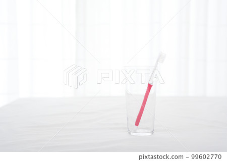 A red-handled toothbrush in a glass cup A red-handled toothbrush in a glass cup 99602770