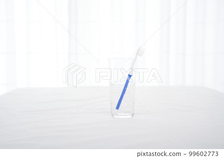 一把藍色手柄的牙刷卡在玻璃杯裡 一把藍色手柄的牙刷卡在玻璃杯裡 99602773