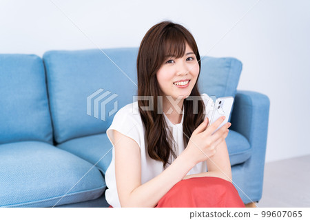一位年輕女子在明亮的客廳裡使用智能手機 99607065