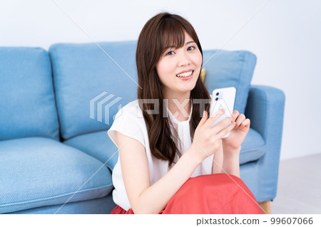 A young woman using a smartphone in a bright living room A young woman using a smartphone in a bright living room 99607066