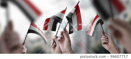 A group of people holding small flags of the Yemen in their hands 99607757