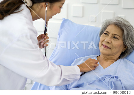 Senior female patient and doctor. Young asian doctor use a stethoscope to check the heartbeat of the elderly patient. 99608013