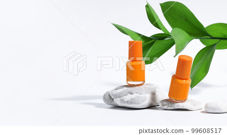 Manicure or pedicure background. Creative mockup of isolated cosmetics bottles with orange nail polish with plant, on stone, on white background with hard shadows from plants. Banner 99608517