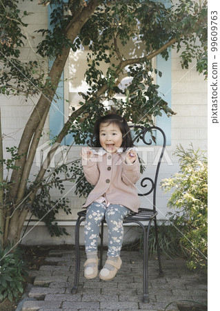 Toddler sitting in a nice chair outdoors 99609763