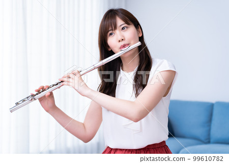 A woman blowing a flute 99610782