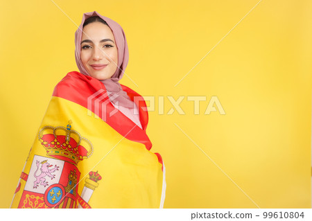 Happy muslim woman wrapping with spanish national flag 99610804
