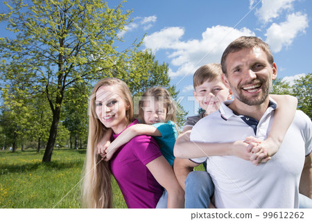 Parents giving piggyback ride to children Parents giving piggyback ride to children 99612262