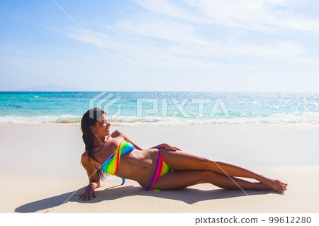 Woman in swimsuit laying on beach Woman in swimsuit laying on beach 99612280