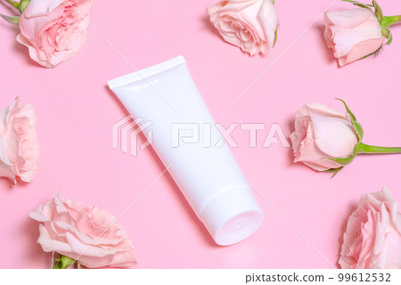 White empty cosmetic tube, on a pink background with delicate pink roses. White empty cosmetic tube, on a pink background with delicate pink roses. 99612532