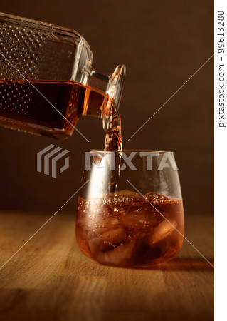 Whiskey is poured into a dammed glass with ice. 99613280