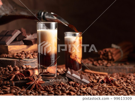 Irish cream and coffee liquor is poured from a bottle into a glass. 99613309