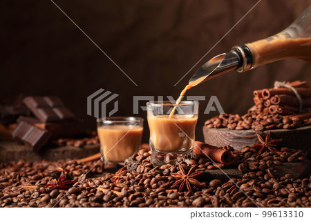 Irish cream and coffee liquor is poured from a bottle into a glass. Irish cream and coffee liquor is poured from a bottle into a glass. 99613310