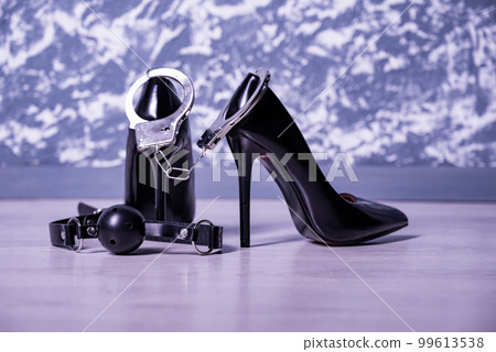 Adult sex games. Kinky lifestyle. Pair of black high-heeled shoes with gag ball and handcuffs. Bdsm outfit 99613538