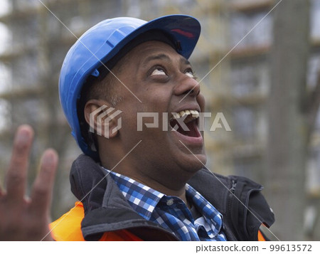 Close up portrait of a laughing Somali civil engineer wearing protective vest and helmet at work on construction site Close up portrait of a laughing Somali civil engineer wearing protective vest and helmet at work on construction site 99613572