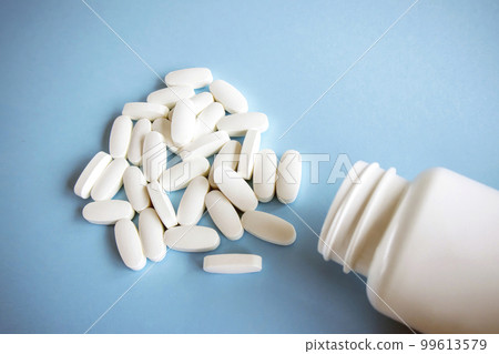 L glutamine white oval tablets lie on a blue background next to the jar. 99613579