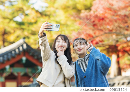 Woman going on an autumn trip with her friends and taking pictures with a smartphone 99615524