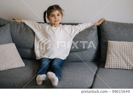 Cute little girl sitting on sofa at home. Home mood 99615649