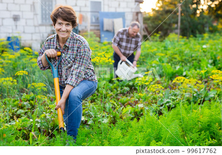 woman farmer posing and digging in her estate garden 99617762