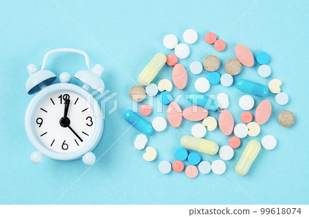 Medicine time. High angle view of colorful medicines and pills on alarm clock. Medicine time. High angle view of colorful medicines and pills on alarm clock. 99618074