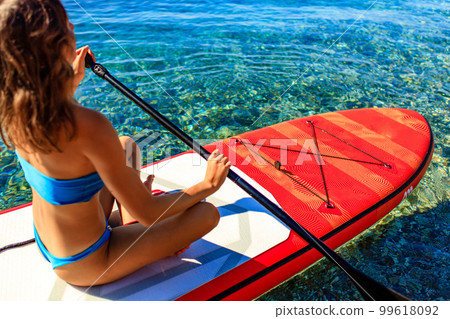 Woman paddling on sup board with mountains on background 99618092