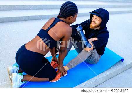 smiling young mixed race couple in sportswear warming up outdoors sity background early morning smiling young mixed race couple in sportswear warming up outdoors sity background early morning 99618155
