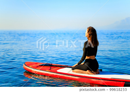 beautiful woman practising yoga on paddle sup surfboard beautiful woman practising yoga on paddle sup surfboard 99618233