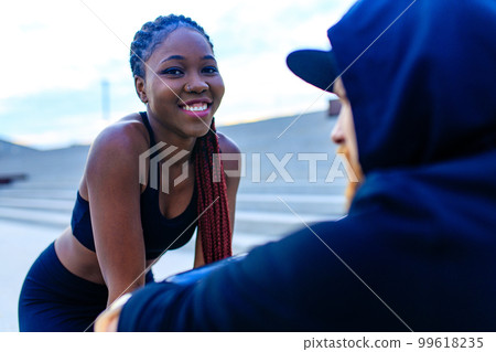 spain woman with afro pigtails crossfit trainer motivating her boyfriend for morning running outdoors in sity 99618235