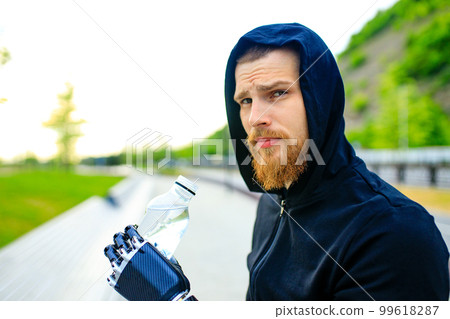 man with arm prosthesis in sports clothing ready for morning workout outdoors. Disabled sport concept 99618287