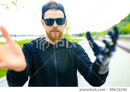 young bearded man with metal arm prosthetic outdoor young bearded man with metal arm prosthetic outdoor 99618290