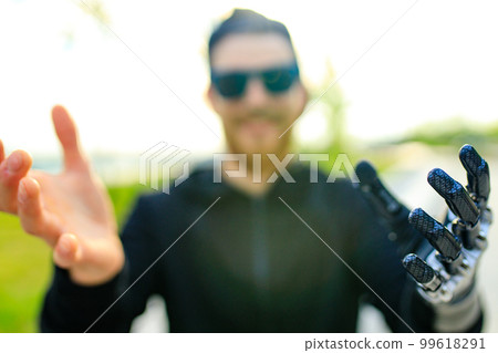 young bearded man with metal arm prosthetic outdoor young bearded man with metal arm prosthetic outdoor 99618291