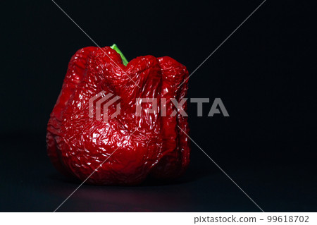 wrinkled old red sweet bell pepper on a dark black background close-up wrinkled old red sweet bell pepper on a dark black background close-up 99618702