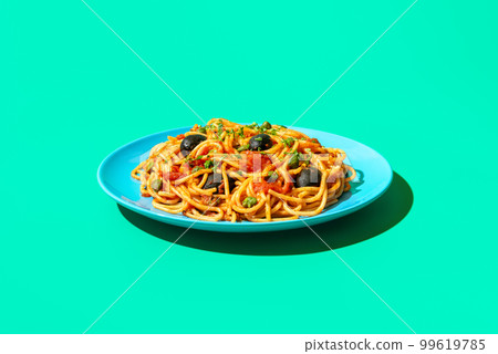 Spaghetti puttanesca plate in bright light, minimalist on a green background Spaghetti puttanesca plate in bright light, minimalist on a green background 99619785